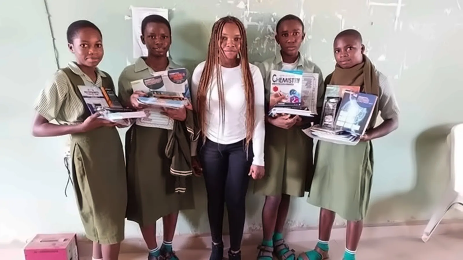 Students holding new chemistry and science textbooks with a volunteer
