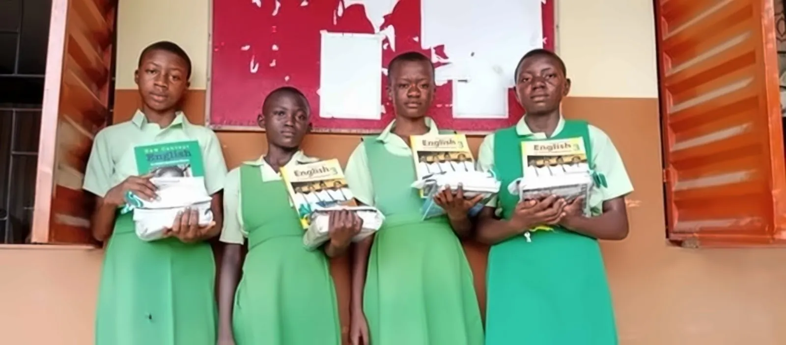 Four girls in green uniforms holding English textbooks