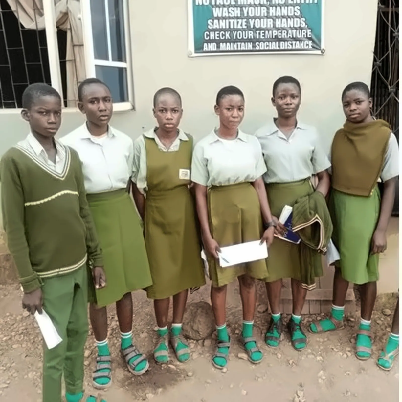 Girls in green school uniforms holding sponsorship letters