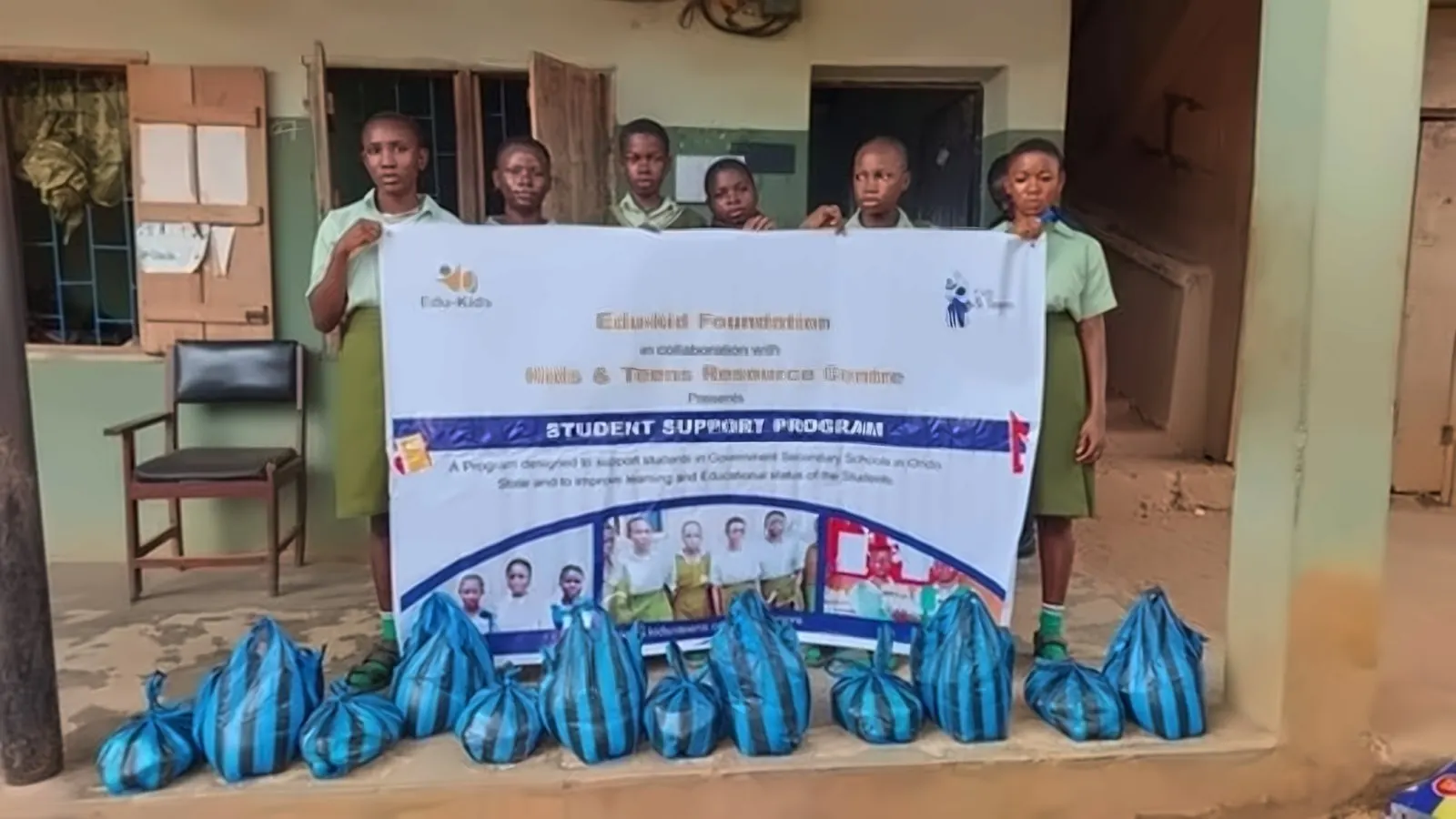 Students beside the Student Support Programme banner and supply bags